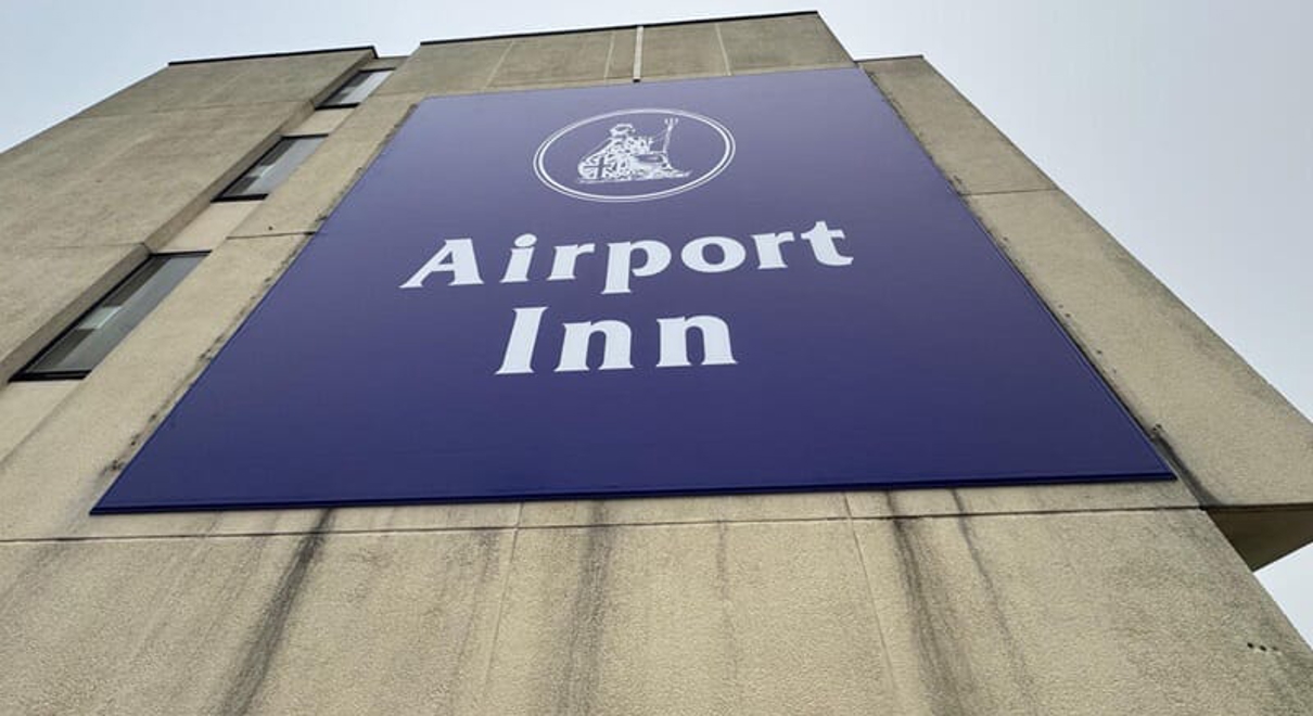 An image of the blue Airport Inn signage on the top of the building.